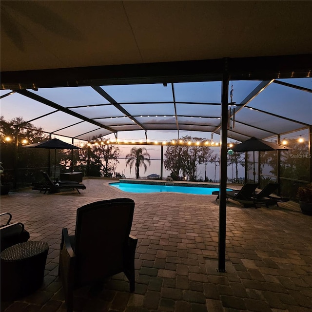 patio terrace at dusk with a lanai and a fenced in pool