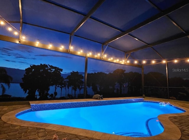 pool at night featuring a patio, a lanai, and an outdoor pool