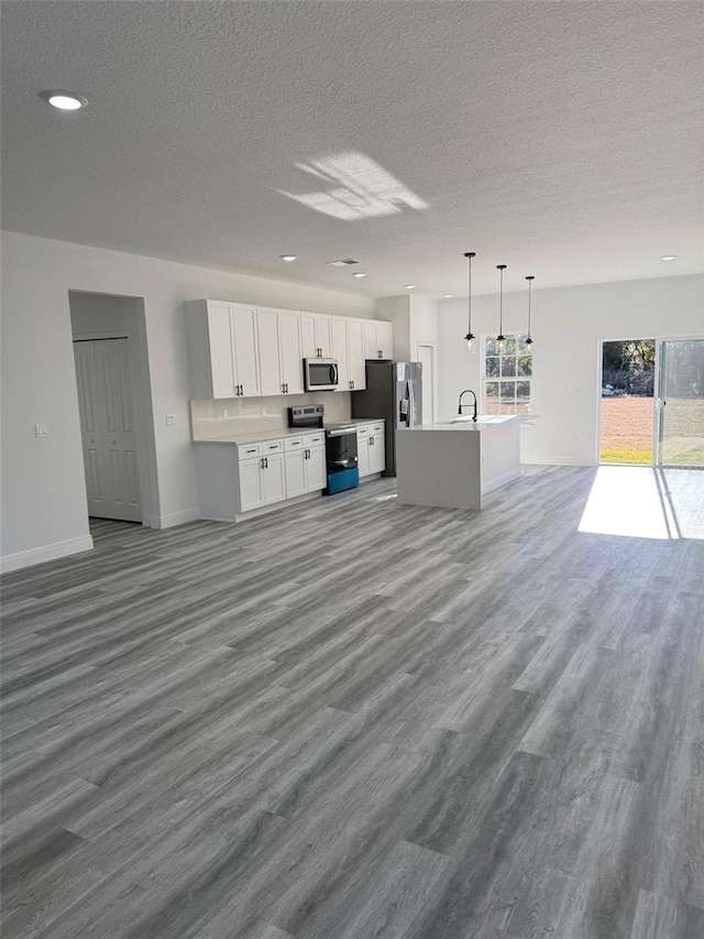 kitchen featuring pendant lighting, sink, white cabinets, a center island, and stainless steel appliances