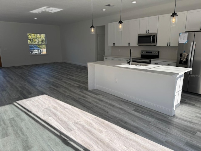 kitchen featuring white cabinetry, stainless steel appliances, a center island with sink, and pendant lighting