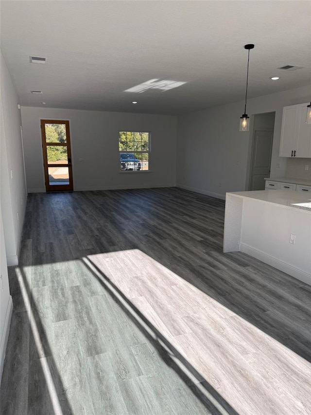 unfurnished living room featuring dark hardwood / wood-style floors and a healthy amount of sunlight