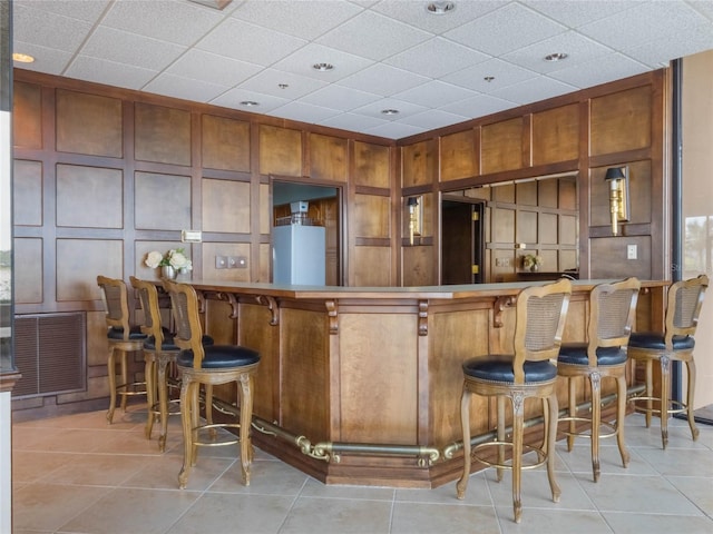 bar featuring light tile patterned floors and a drop ceiling