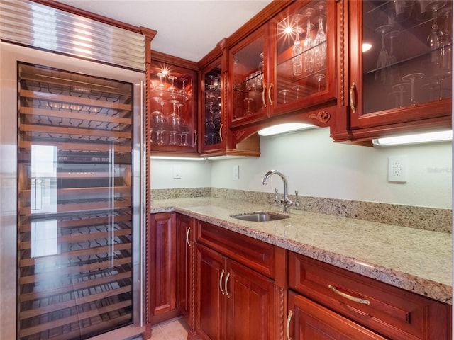 interior space featuring light tile patterned floors, sink, light stone counters, and wine cooler