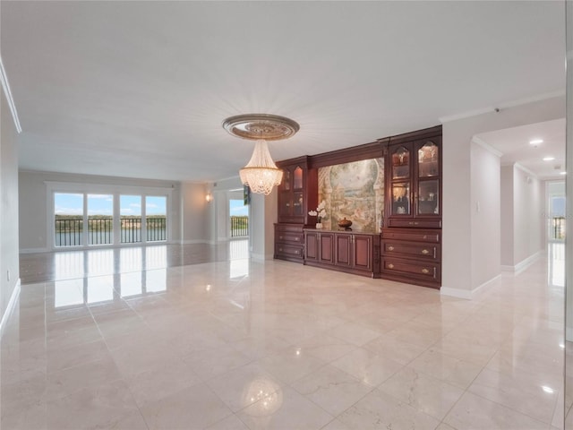 empty room featuring crown molding, an inviting chandelier, and a water view