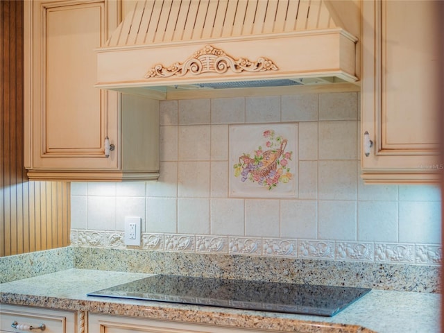 kitchen with light stone countertops, black electric stovetop, custom exhaust hood, and tasteful backsplash