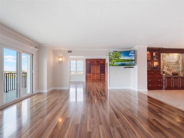 unfurnished living room with hardwood / wood-style floors and crown molding