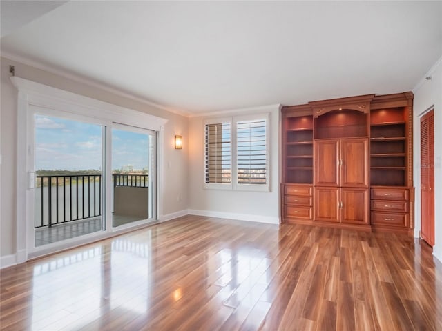 unfurnished living room with wood-type flooring and ornamental molding