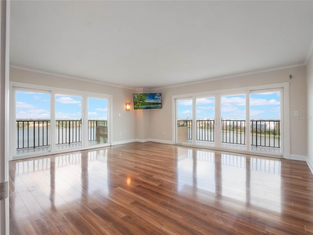 unfurnished room with hardwood / wood-style floors, crown molding, and a wealth of natural light