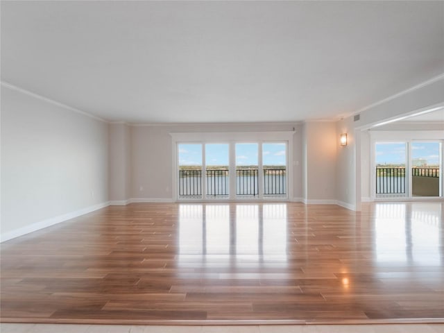 spare room featuring a water view, wood-type flooring, and crown molding