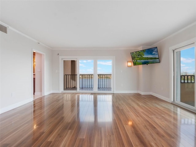 empty room with plenty of natural light, crown molding, and hardwood / wood-style floors