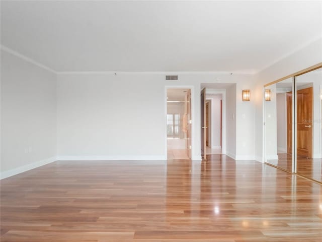 empty room with ornamental molding and light hardwood / wood-style floors