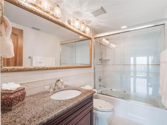 full bathroom featuring toilet, vanity, and bath / shower combo with glass door