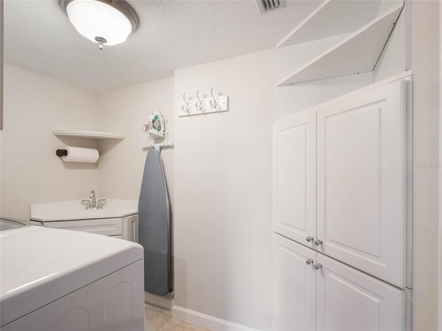 laundry room with washer and dryer, a textured ceiling, and cabinets