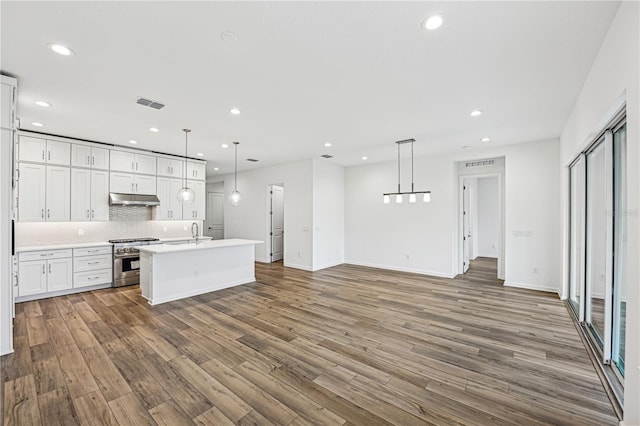 kitchen with under cabinet range hood, white cabinets, light countertops, high end stainless steel range oven, and pendant lighting