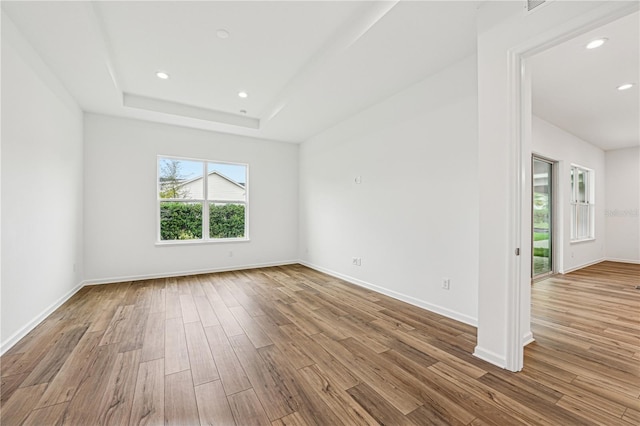 unfurnished room with baseboards, a tray ceiling, light wood finished floors, and recessed lighting