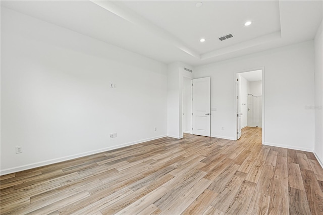 unfurnished bedroom with light wood-style flooring, recessed lighting, visible vents, baseboards, and a tray ceiling