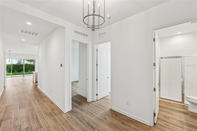 hall featuring light wood-type flooring, baseboards, and visible vents