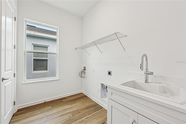 laundry area featuring hookup for a washing machine, hookup for an electric dryer, a sink, light wood-type flooring, and baseboards