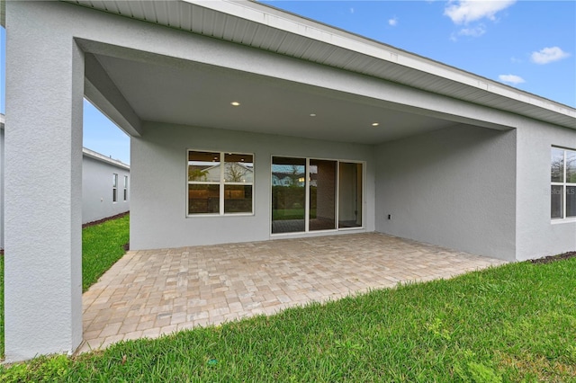 back of house with a lawn, a patio area, and stucco siding