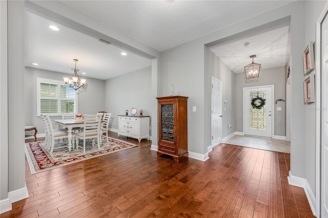 entryway featuring an inviting chandelier, baseboards, visible vents, and dark wood-style flooring