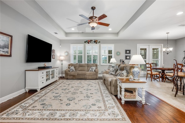 living area with plenty of natural light, baseboards, a raised ceiling, and wood finished floors