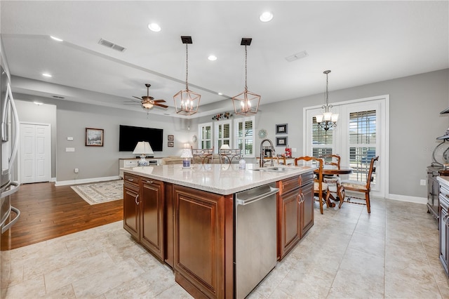 kitchen featuring a sink, visible vents, open floor plan, dishwasher, and an island with sink