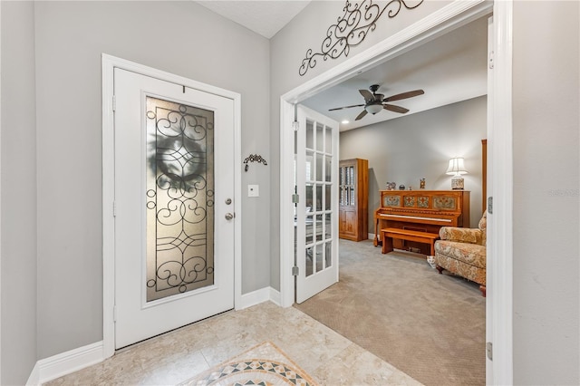 entrance foyer with baseboards, a ceiling fan, and light colored carpet