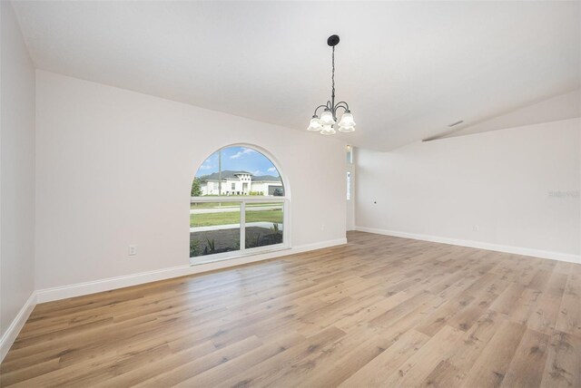 1001 Glencove Ave NW, Palm Bay, FL 32907 - empty room featuring light wood-style floors, vaulted ceiling, baseboards, and a notable chandelier