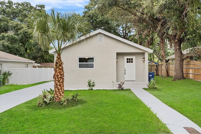 view of front facade featuring a front yard, fence, and stucco siding