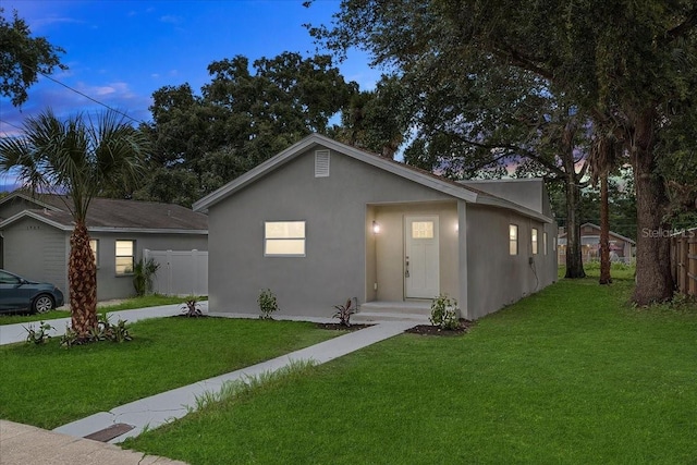 ranch-style home with a front yard, fence, and stucco siding