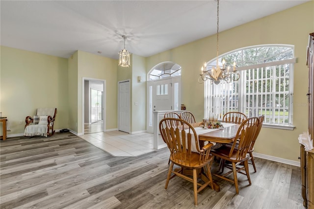 dining space featuring light wood-type flooring, an inviting chandelier, and plenty of natural light