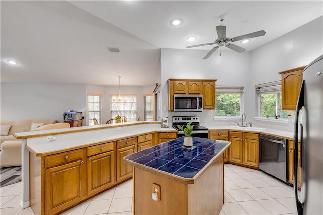 kitchen featuring stainless steel appliances, tile counters, pendant lighting, a center island, and sink