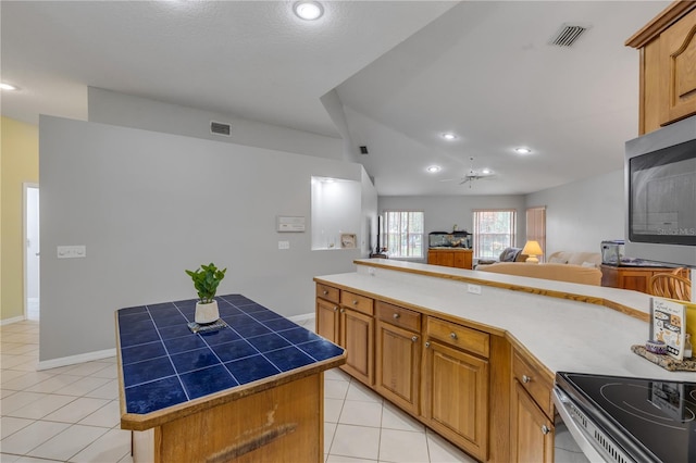 kitchen with light tile patterned floors, tile countertops, and a center island