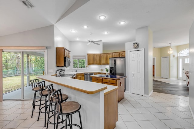 kitchen with lofted ceiling, stainless steel appliances, a breakfast bar, and light tile patterned floors