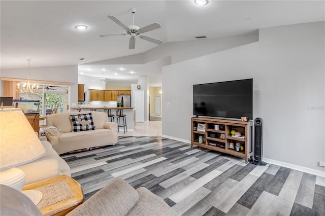 living room featuring ceiling fan with notable chandelier, light wood-type flooring, a textured ceiling, and lofted ceiling