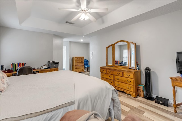 bedroom featuring a tray ceiling, ceiling fan, and light hardwood / wood-style floors