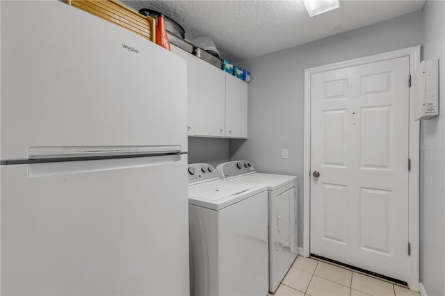 washroom featuring cabinets, light tile patterned floors, washer and clothes dryer, and a textured ceiling