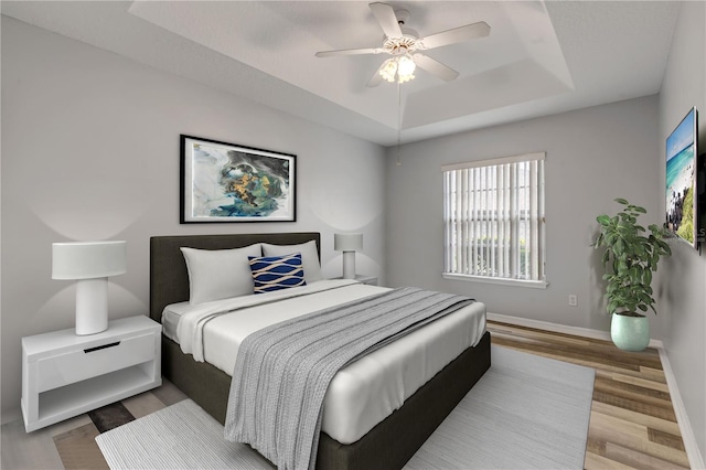 bedroom featuring a tray ceiling, hardwood / wood-style floors, and ceiling fan