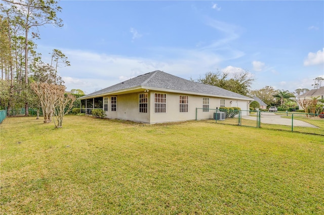 rear view of property with central AC unit and a lawn