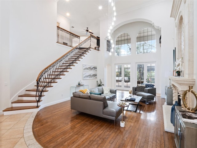 living room with hardwood / wood-style flooring, a high ceiling, ceiling fan, crown molding, and french doors