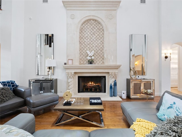 living room featuring a premium fireplace, hardwood / wood-style floors, and a high ceiling