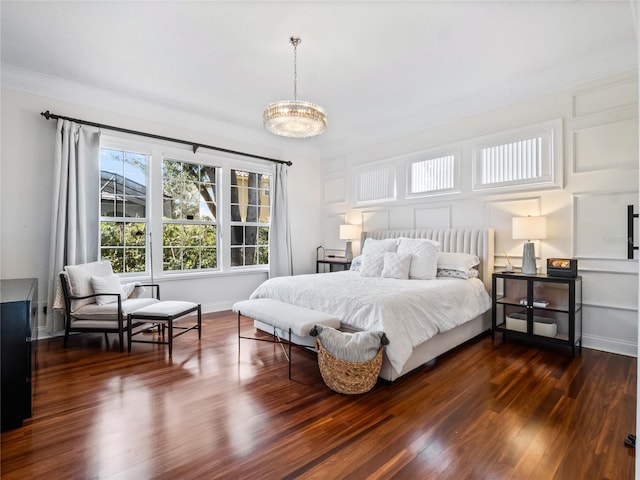 bedroom featuring dark wood-type flooring, crown molding, and an inviting chandelier