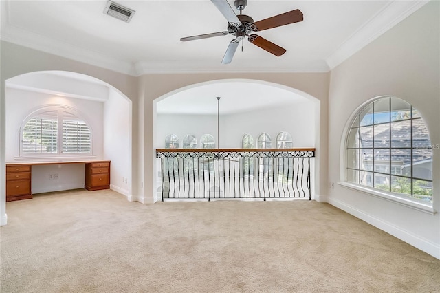 carpeted spare room with crown molding, plenty of natural light, and ceiling fan