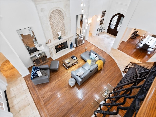 tiled living room with a towering ceiling, a high end fireplace, and french doors