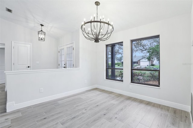 unfurnished dining area featuring an inviting chandelier, light wood-style flooring, and baseboards