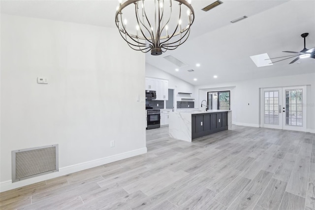 unfurnished living room with lofted ceiling with skylight, visible vents, and light wood finished floors