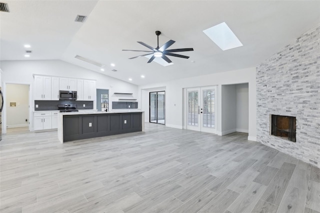 kitchen featuring open floor plan, appliances with stainless steel finishes, a kitchen island with sink, and white cabinetry