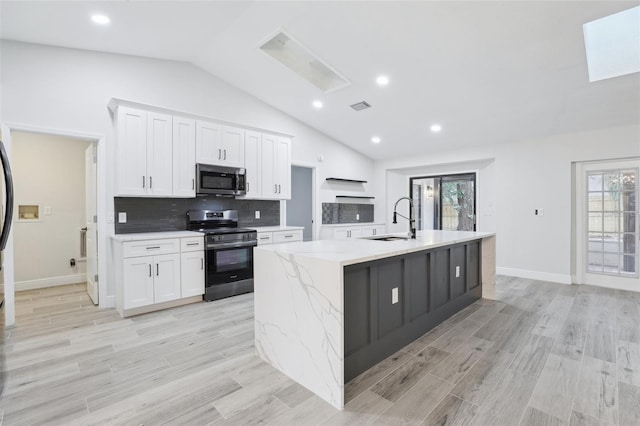 kitchen with a center island with sink, visible vents, white cabinets, appliances with stainless steel finishes, and a sink