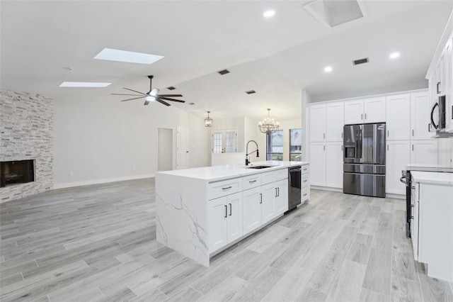 kitchen featuring a sink, refrigerator with ice dispenser, white cabinetry, open floor plan, and black dishwasher