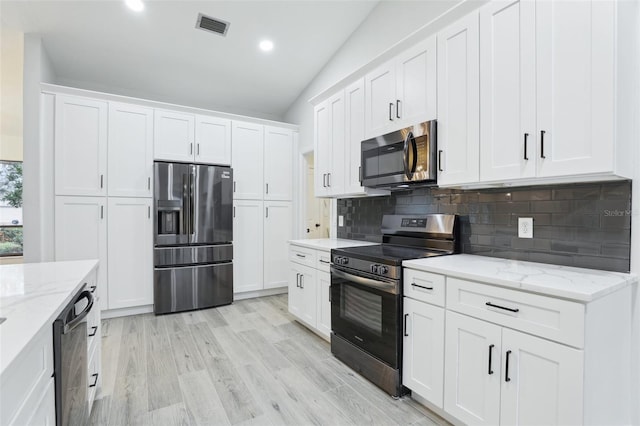 kitchen with appliances with stainless steel finishes, white cabinets, visible vents, and light stone countertops